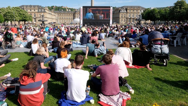Viele Menschen sitzen auf dem Schlossplatz und schauen einen Film auf der Leinwand: Allein dort werden beim Internationalen Filmfestival Stuttgart 2024 über 100 Filme gezeigt.