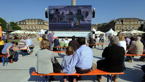 Eine Familie sitzt auf dem Schlossplatz und schaut einen Film: Die Filme auf dem Schlossplatz Stuttgart sind für Groß und Klein  seit Jahren eines der Highlights des Trickfilmfestivals. (Foto: dpa Bildfunk, Picture Alliance)