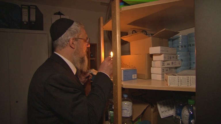 Rabbi spürt im Licht eines Streichholzes mit einer Vogelfeder Krümel auf. Das gehört zur rituellen Reinigung vor dem Pessach-Fest. (Foto: SWR)