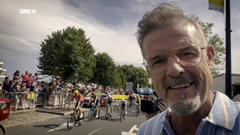 Sportmoderator Michael Antwerpes vor dem Spitzenfeld der Tour de France, das ins Etappenziel einfährt (Foto: SWR, SWR/Michael Antwerpes)