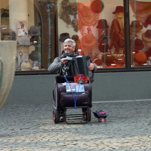 Älterer Herr sitzt in der Fußgängerzone und spielt Akkordeon (Foto: SWR)