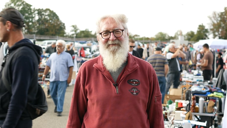Mann steht auf einem Flohmarkt
