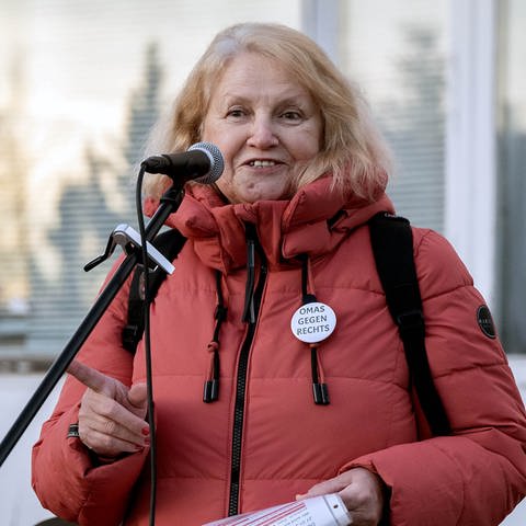 Die Gründerin von „Omas gegen Rechts” Anna Ohnweiler ist bei einer Demonstration und steht auf einer Bühne. Sie steht an einem Mikrofon und schaut in die Kamera. (Foto: Anna Ohnweiler)