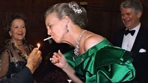 Königin Margrethe II. von Dänemark raucht in einem glänzend grünen Kleid bei einem Galadinner. Sie wurde auch die Vulkankönigin genannt.