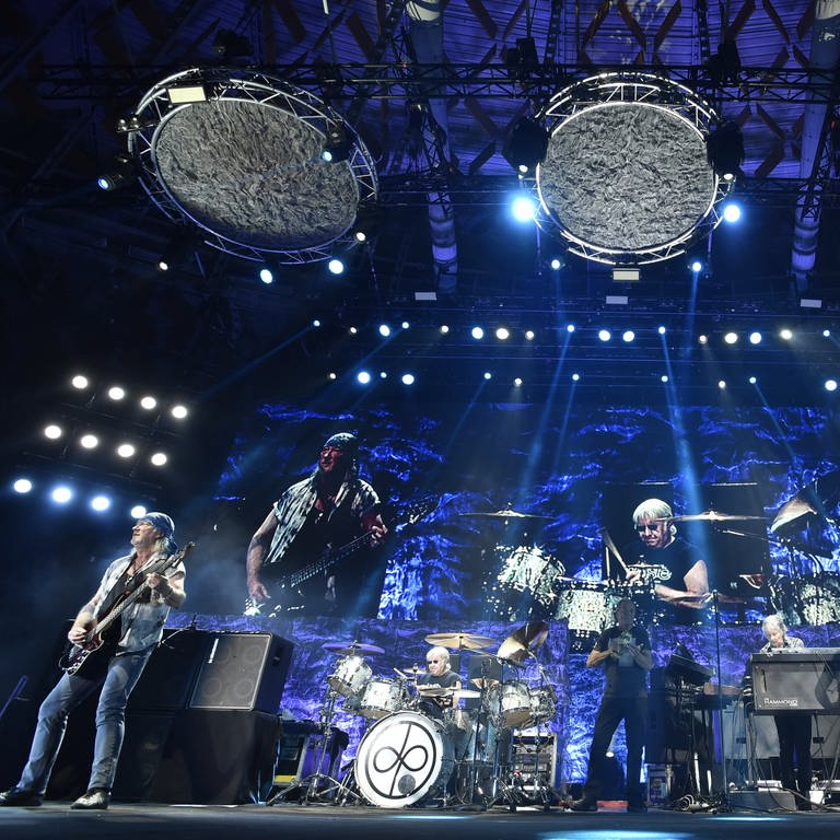 Die Musiker der Band "Deep Purple" stehen in einem blauen Licht auf der Bühne und machen Musik.