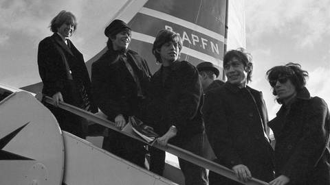 Die Rollings Stones vor einem Flugzeug in 1964
