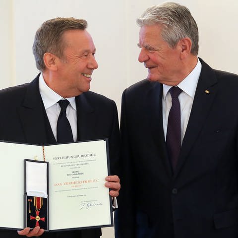 Bundespräsident Joachim Gauck (r) verleiht das Bundesverdienstkreuz an den Sänger Roland Kaiser