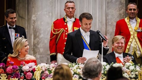 Während Präsident Macron eine Rede hält lachen Königin Máxima und König Willem-Alexander (Foto: IMAGO, IMAGO / ANP)