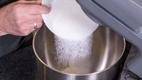 Zucker für den Teig wird in die Rührschüssel gegeben. Dann wird laut Rezept der Kuchenteig für den Kuchen im Glas einige Zeit gerührt. (Foto: SWR, Corinna Holzer)