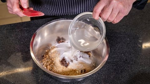Walnüsse, Brösel, gehackte Rosinen und Zucker werden in eine Rührschüssel gegeben.