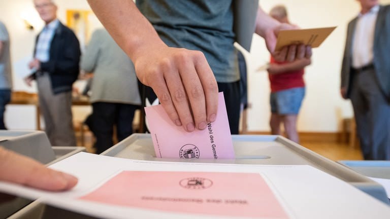 Symbolbild: Ein Mann wirft seinen Stimmzettel für die Kommunalwahl in Baden-Württemberg ein. 