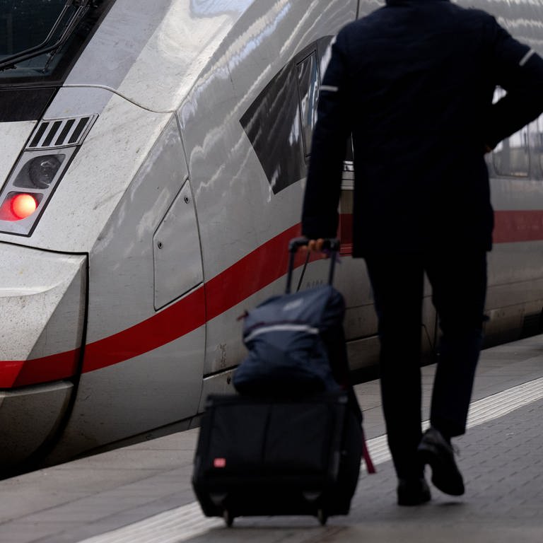 Ein Mitarbeiter der Deutschen Bahn (DB) geht zu einem Zug.