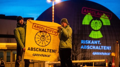 Greenpeace-Aktivisten protestieren vor dem Kernkraftwerk Neckarwestheim, im Hintergrund die Lichtprojektion. (Foto: picture-alliance / Reportdienste, picture alliance/dpa | Christoph Schmidt)