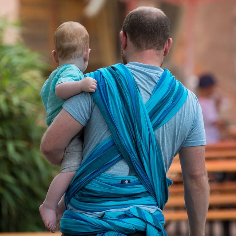 Ein Mann hält ein Baby auf dem Arm. 