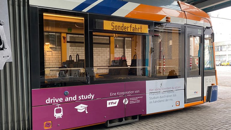Eine Straßenbahn der rnv ist mit den Farben der Kooperations-Hochschule HdWM lila foliert, darauf steht "drive & study"