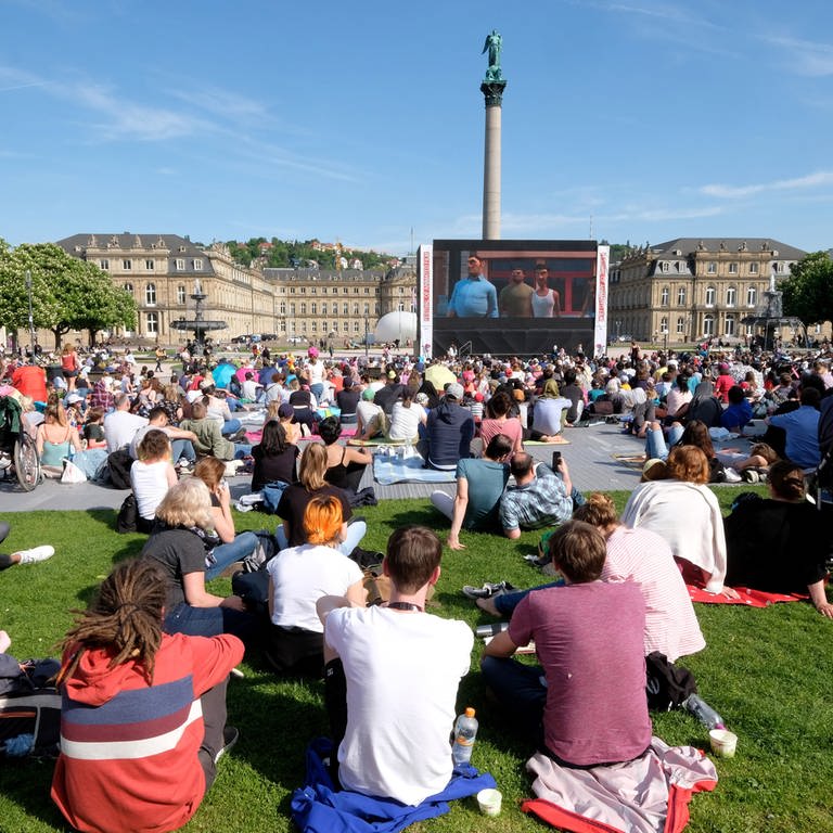 Viele Menschen sitzen auf dem Schlossplatz und schauen einen Film auf der Leinwand: Allein dort werden beim Internationalen Filmfestival Stuttgart 2024 über 100 Filme gezeigt. (Foto: dpa Bildfunk, Picture Alliance)