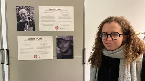 Junge Frau mit Brille neben einer Stellwand: Sie hat Studentinnen und Studenten in der Ukraine fotografiert, die später im Krieg gestorben sind. In Erinnerung an sie gibt es eine Ausstellung in Tübingen.