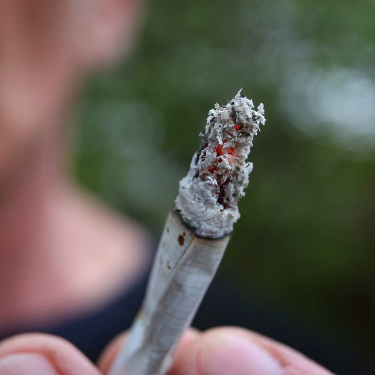 Ein Mann hält einen Joint. Ab dem 1. April ist durch das Cannabis-Gesetz der Konsum der Droge teilweise erlaubt.