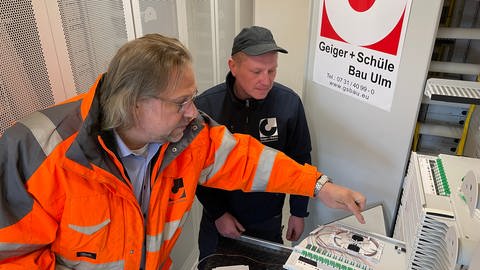 Rolf Mezger, Geschäftsführer von Geiger + Schüle Bau (links), im Gespräch mit Glasfasermonteur Valerii Saramotin. An der Baustelle in der Zeitblomstraße werden Glasfaserleitungen verlegt.
