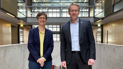 Korrespondentin Eva Ellermann und Ministerpräsident Daniel Günther stehen in der Halle des ARD Hauptstadtstudios nebeneinander und lächeln in die Kamera