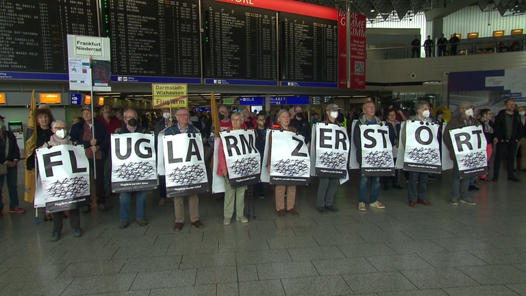 Fluglärm-Gegener formieren sich am Flughafen Frankfurt und bilden mit ihren Schildern den Satz: Fluglärm zerstört. 