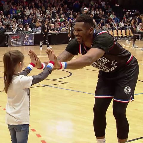 Harlem Globetrotters Spieler klatscht in die Hände mit einer Schülerin
