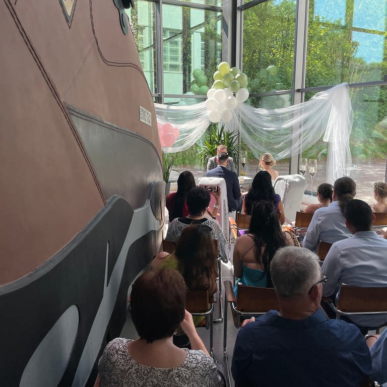Die Hochzeitsgäste und das Brautpaar sitzen direkt neben dem größten Schuh der Welt bei der Trauung.