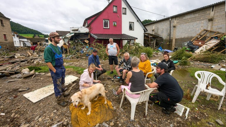 Von ihren Häusern ist nicht viel übrig geblieben. Anwohner sitzen in Schuld zwischen Trümmerbergen. (Foto: dpa Bildfunk, Picture Alliance)