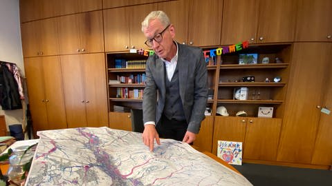 Bürgermeister Guido Orthen schaut auf einer Karte, wo die Starkregengefahren in Bad Neuenahr-Ahrweiler am größten sind.  (Foto: SWR)