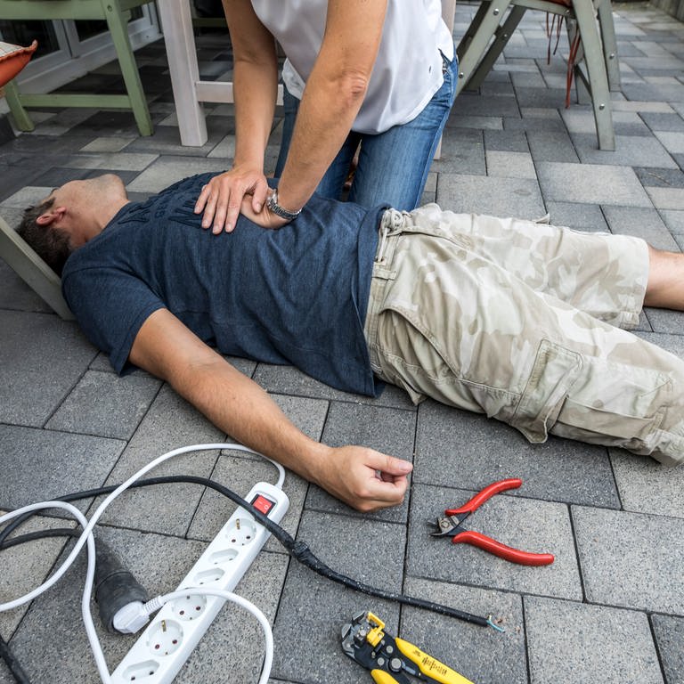 Ein Mann liegt bewusstlos am Boden und wird mit Herz-Druck-Massage reanimiert. (Foto: picture-alliance / Reportdienste, picture alliance / Jochen Tack | Jochen Tack)