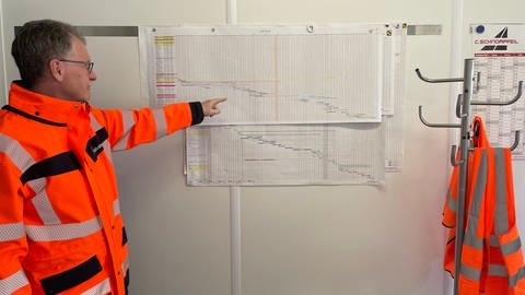 Dauerbaustelle A1: Warum Autofahrer dort keine freie Fahrt haben - Bauingenieur Uwe Schminke zeigt im Bausbesprechungsbüro auf den Zeitplan der aktuellen Baumaßnahme