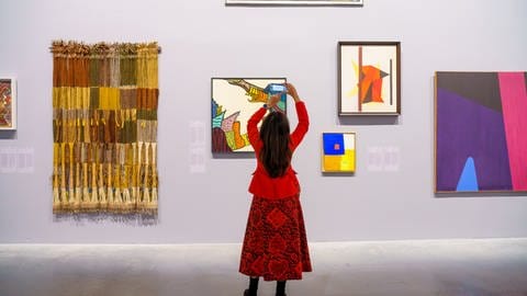 Eine Frau, in rot gekleidet, fotografiert Bilder in einem Ausstelungsraum  (Foto: La Biennale di Venezia)