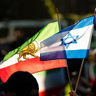 Ein Mann hält eine israelische (r) und eine iranische Fahne (Foto: picture-alliance / Reportdienste, picture alliance/dpa | Jonas Walzberg)