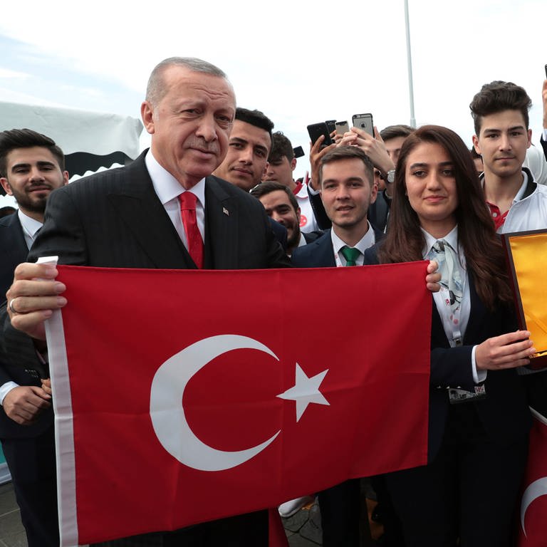 Dieses vom Presidential Press Service zur Verfügung gestellte Bild zeigt Recep Tayyip Erdogan (l), Präsident der Türkei, der eine türkische Nationalflagge hochhält