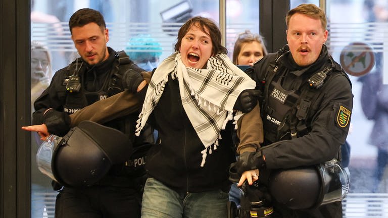 Polizisten führen während der Besetzung des Audimax der Universität Leipzig eine junge Frau ab