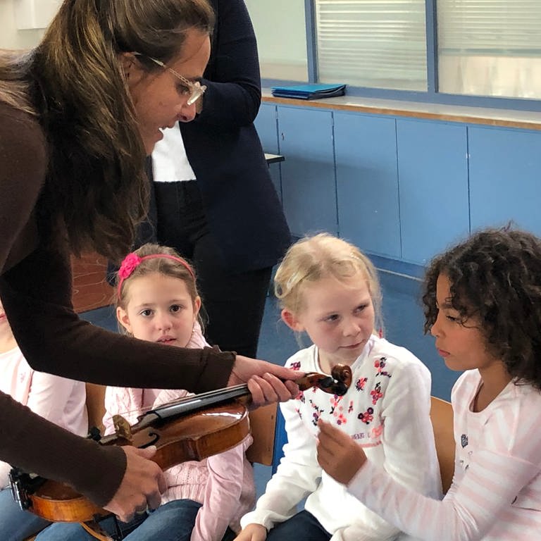 Frau zeigt Schulkindern eine Geige