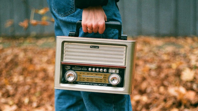 Ein Mann hat ein Radio in der Hand, das er im Freien trägt 