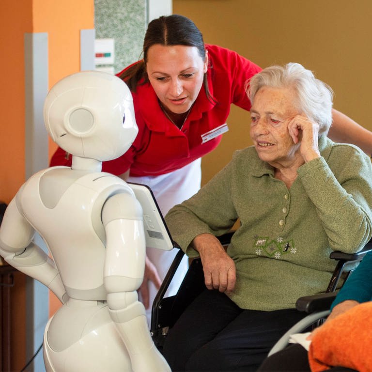 Der humanoide Roboter Pepper kommuniziert in einem Seniorenwohnhaus in Bischofswerda mit Bewohnerinnen und einer Pflegekraft