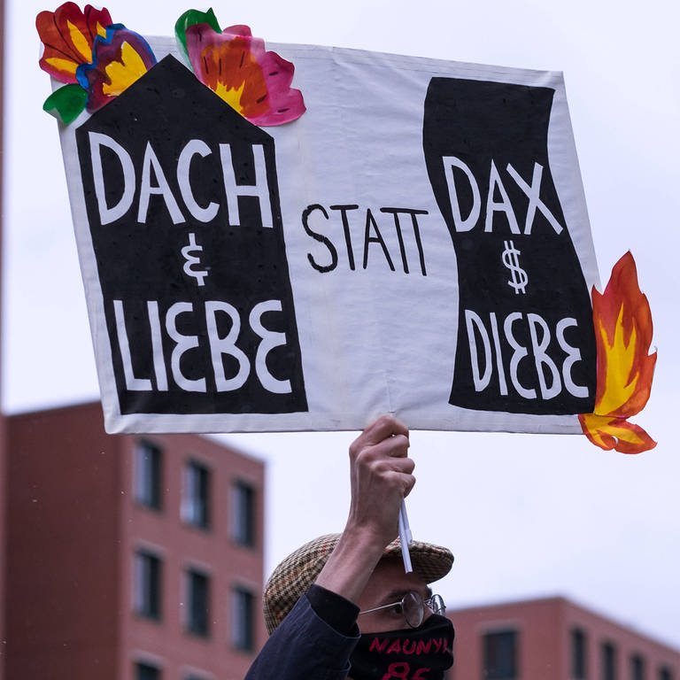 Demonstration für bezahlbaren Wohnraum. Transparent mit der Aufschrift: "Dach und Liebe statt DAX und Diebe"