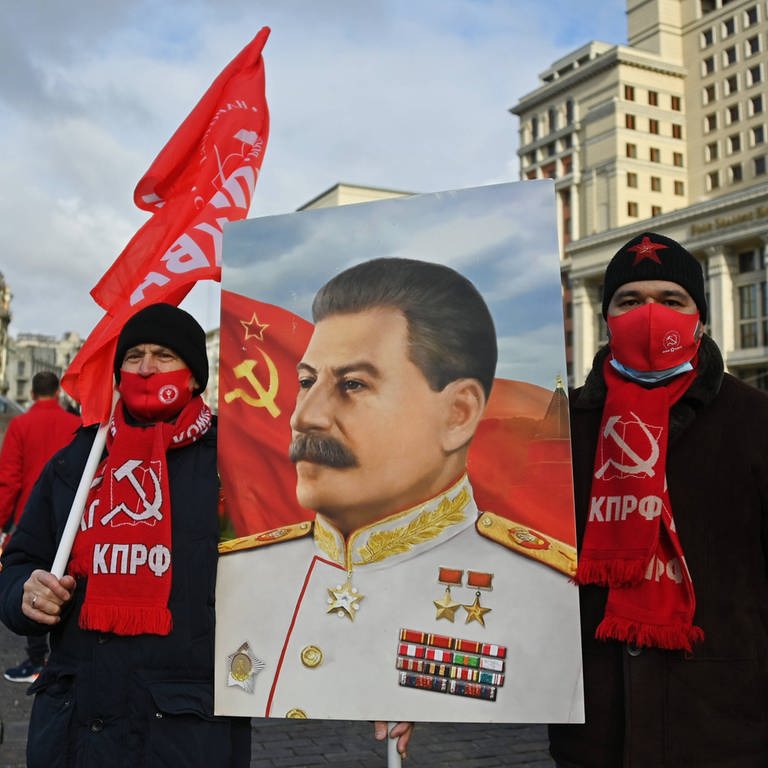 Am Todestag von Stalin, der am 5. März 1953 starb, nehmen im März 2022 Mitglieder der Kommunistischen Partei Russlands an einer Blumenniederlegungszeremonie am Grab des sowjetischen Führers Joseph Stalin an der Kremlmauer teil. Vor sich tragen sie ein Porträt Stalins. (Foto: IMAGO, IMAGO / SNA)