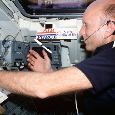 Astronaut Gordon Fullerton beobachtet Kugelschreiber in der Schwerelosigkeit.