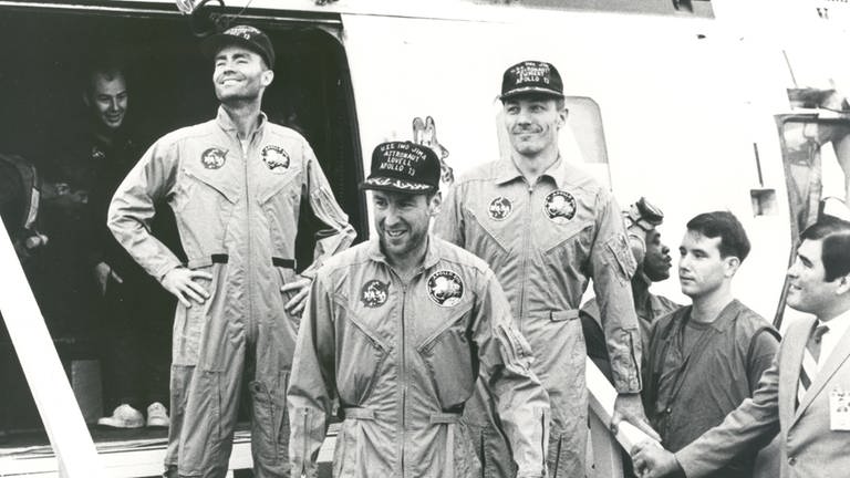 Die Besatzungsmitglieder der Apollo-13-Mission gehen an Bord der USS Iwo Jima, dem Bergungsschiff für die Mission, nach der Wasserung und Bergungsoperationen im Südpazifik: Fred W. Haise, James A. Lovell and John L. Swigert