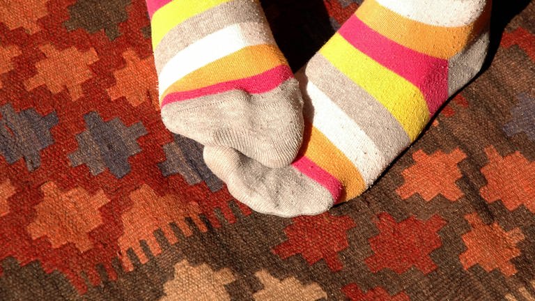 Füße in wärmenden Ringelsocken: Neigen Frauen eher zu kalten Füßen als Männer?