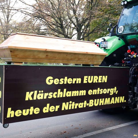 Traktor mit einem echten Sarg und dem Banner: Gestern euren Klaerschlamm entsorgt, heute der Nitrat-Buhmann - Buhmann ist das älteste Wort für den Bauern