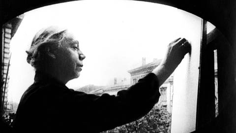Ein Schwarz-Weiss-Foto von Käthe Kollwitz beim Zeichnen vor freiem Himmel