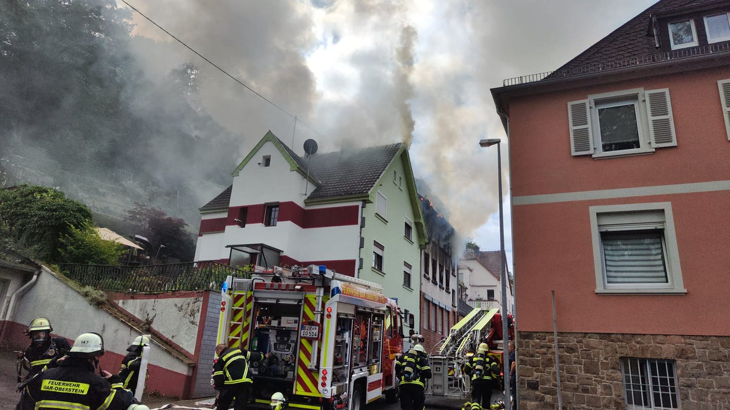 Feuerwehrleute in Idar-Oberstein sind vor dem brennenden Haus in der Treibelsbergstraße im Einsatz.