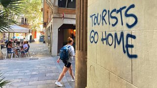Ein an eine Wand im Künstlerviertel Vila de Gràcia gesprühter Schriftzug "Tourists Go Home" in Barcelona