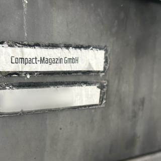 Die Aufschrift "Compact-Magazin GmbH" steht an einem Briefkasten.