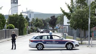 Ein Polizist und ein Polizeiwagen blockieren im Zuge einer Durchsuchung eine Straße in Ternitz, Österreich