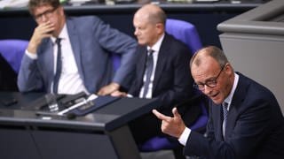 CDU-Chef Friedrich Merz hält im Bundestag eine Rede, im Hintergrund ist Bundeskanzler Scholz zu sehen.